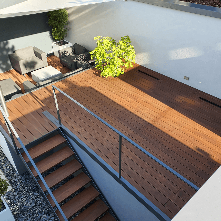 Moderne Dachterrasse mit hochwertigen Bambus-Terrassendielen, stilvollen Gartenmöbeln und grünen Pflanzen. Eine Treppe mit passender Bambus-Beplankung führt zur unteren Etage.