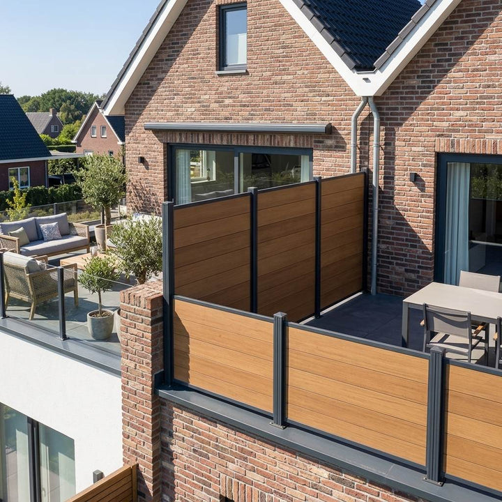 Bambus-Sichtschutzzaun mit anthrazitfarbenen Pfosten auf einer erhöhten Terrasse an einem Backsteinhaus.