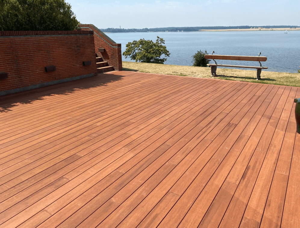 Detailaufnahme einer mehrstufigen Terrasse aus braunen Bambus Terrassendielen neben einem Pool. Die Dielen sind sauber verarbeitet und bilden mehrere Sitz- oder Trittstufen mit exakt ausgeführten Eckverbindungen. Das klare Design und die warme Holzfarbe verleihen dem Außenbereich eine moderne und hochwertige Optik.