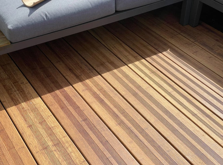 Hochwertige Bambusterrasse mit geriffelten Terrassendielen in der Farbe Sand 20x200x1870 mm und moderner Loungemöblierung. Die warme Holzoptik und das natürliche Lichtspiel unterstreichen die elegante Gestaltung des Außenbereichs.