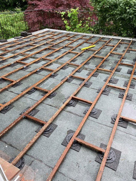 Terrassen-Unterkonstruktion aus Bamubs auf Flachdach mit Stelzlagern und Bautenschutzmatten. Fachgerechte Vorbereitung für langlebige Terrassendielen auf Dachterrassen und Balkonen.