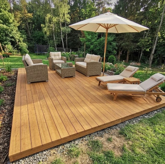 Terrasse aus Campoverde Bambus-Terrassendielen mit Loungegruppe und Sonnenliegen in einem naturnahen Garten.