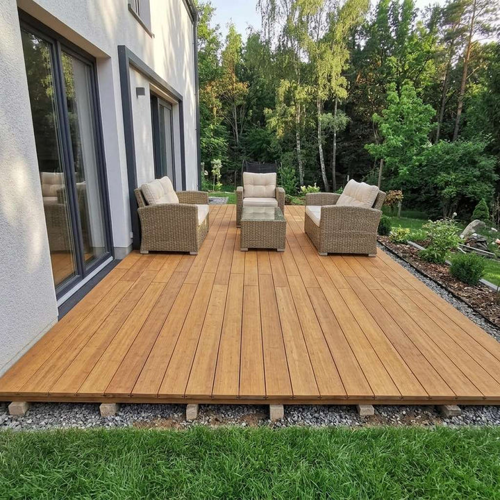 Großzügige Gartenterrasse aus Bambus-Terrassendielen mit Loungemöbeln und Blick in den Garten.