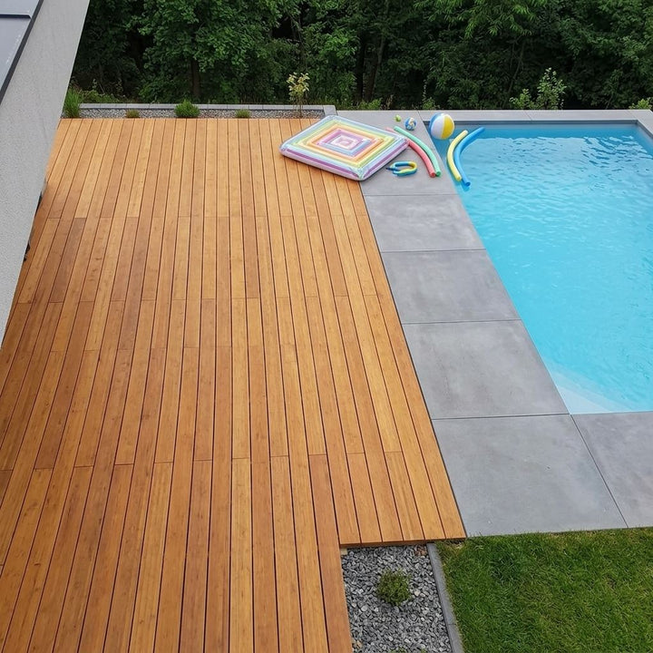 Moderne Gartenterrasse aus Campoverde Terrassendielen mit Loungemöbeln, stimmungsvoller Beleuchtung und Lichterkette in der Abenddämmerung.