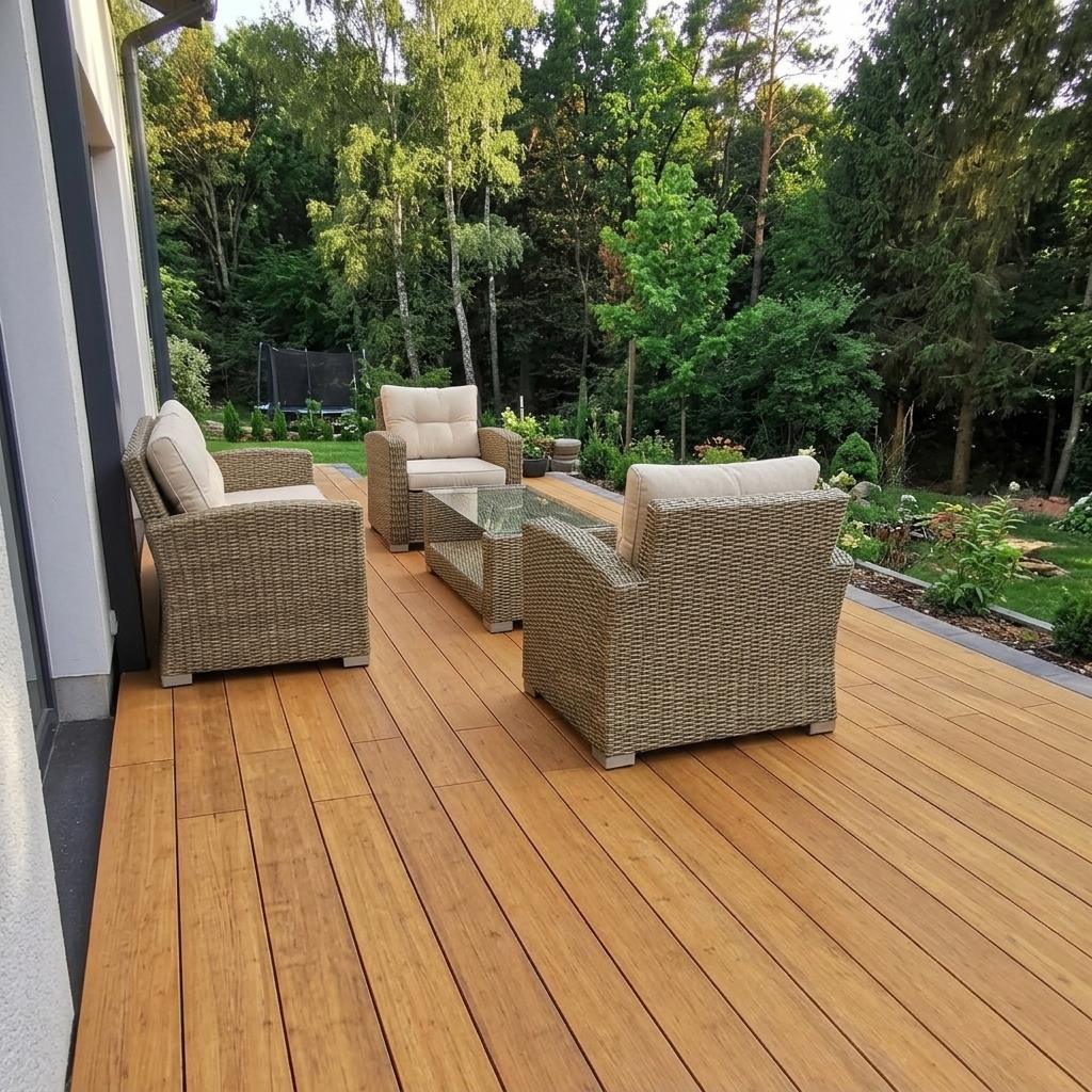 Terrasse mit Desaro Bambus-Terrassendielen, Rattan-Loungemöbeln und Blick in einen grünen Garten.